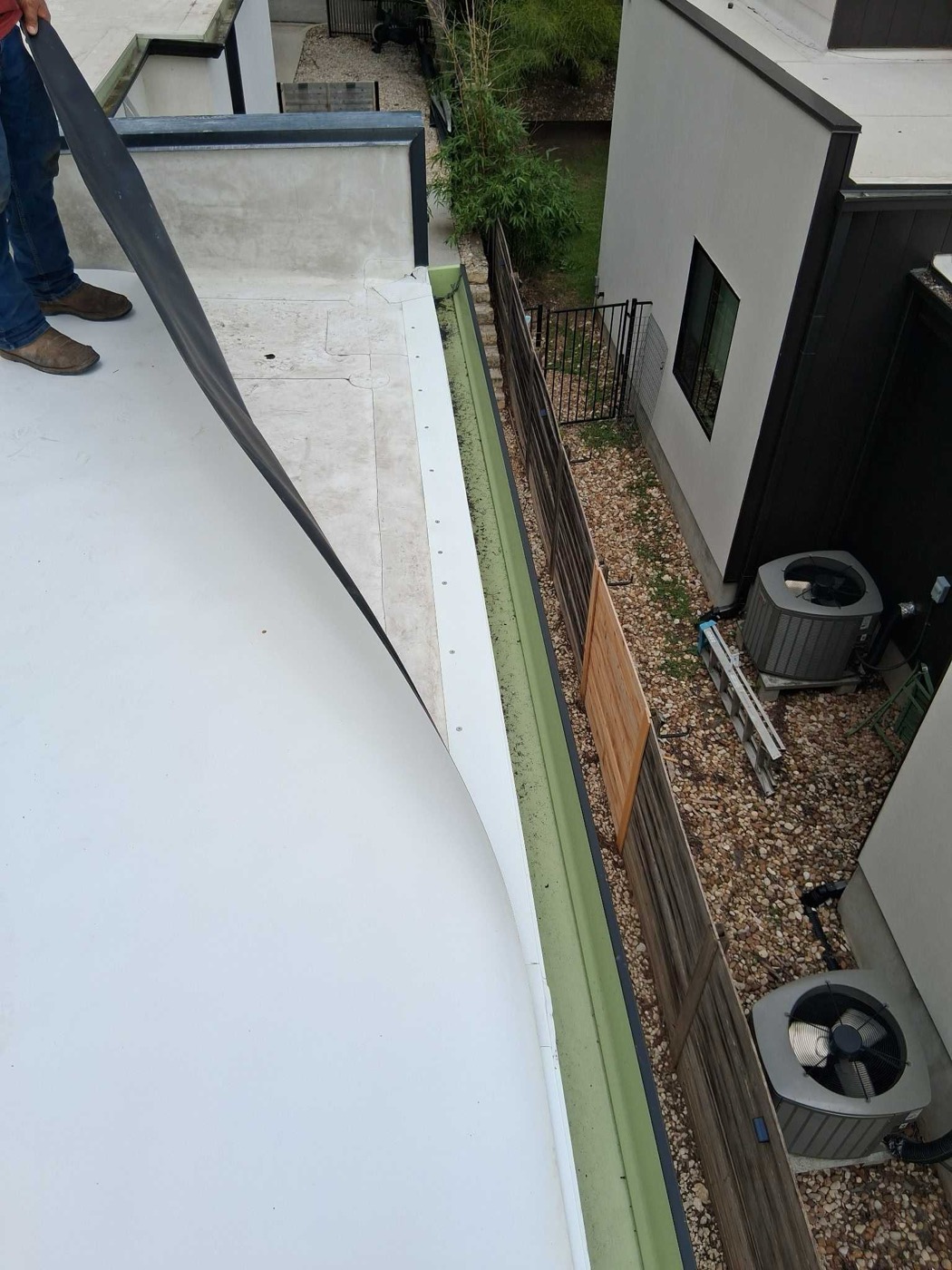 AAR crew member rolling out white TPO membrane on a flat roof in Austin