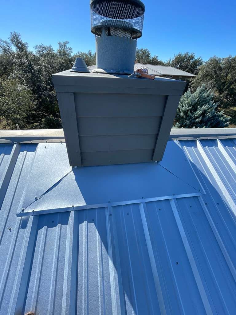 Hand-built cricket flashing behind a roof vent with custom welded metal panels so water sheds around the obstacle