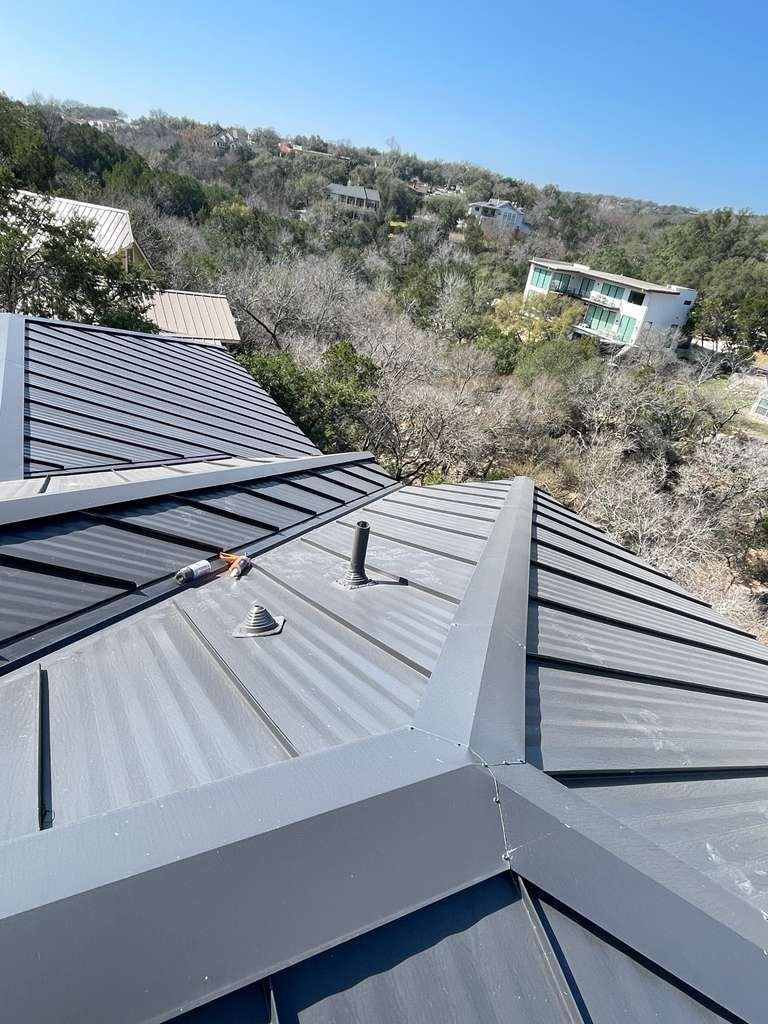 Charcoal standing seam metal roof on a Hill Country home with finished install and hand-folded ridge and valley details, pulled from REPS CompanyCam