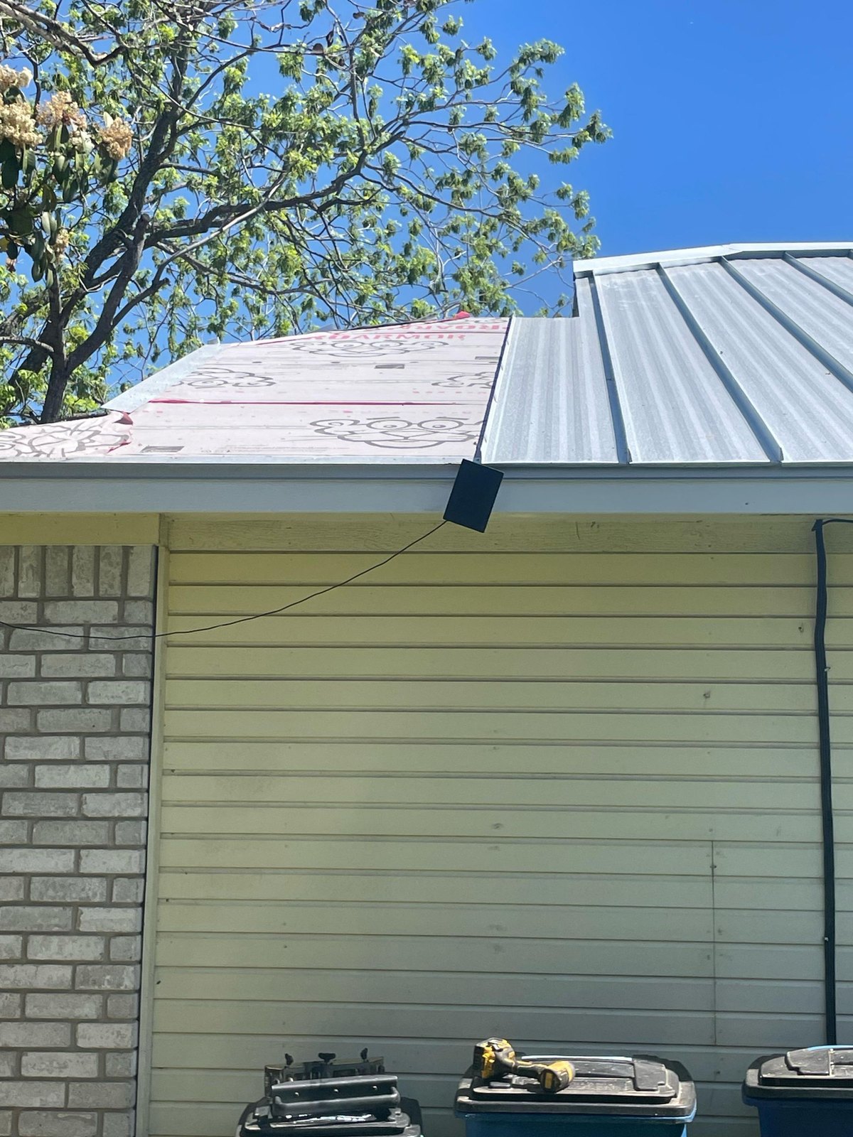 Mid-install standing seam roof transitioning from synthetic underlayment to finished panels on a Central Texas residential project