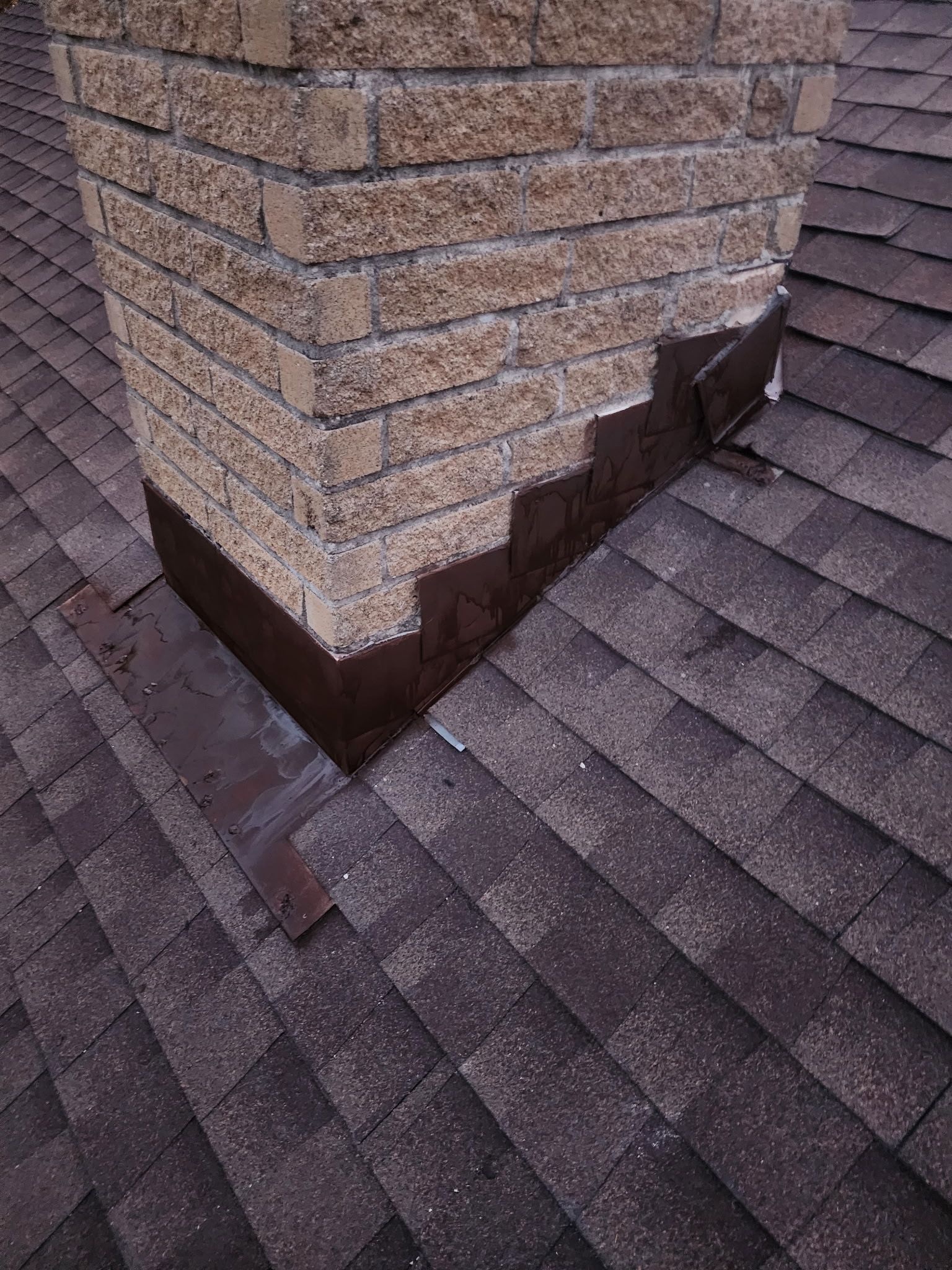 Chimney base flashing detail · hand-cut metal pieces sealed to the brick course before the shingle field goes back