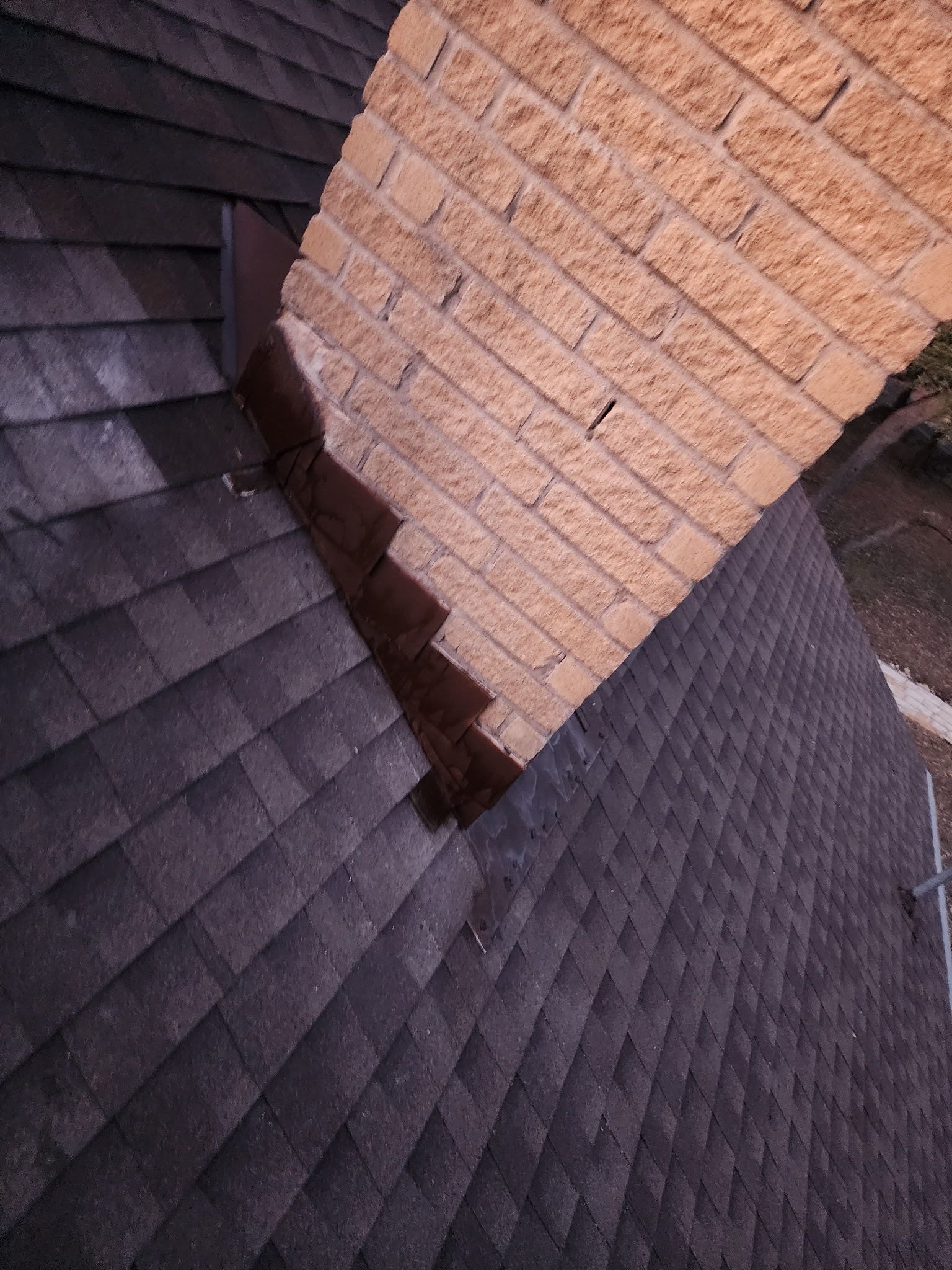 Hand-cut step flashing on a chimney from a CompanyCam project · stepped metal woven into each shingle course