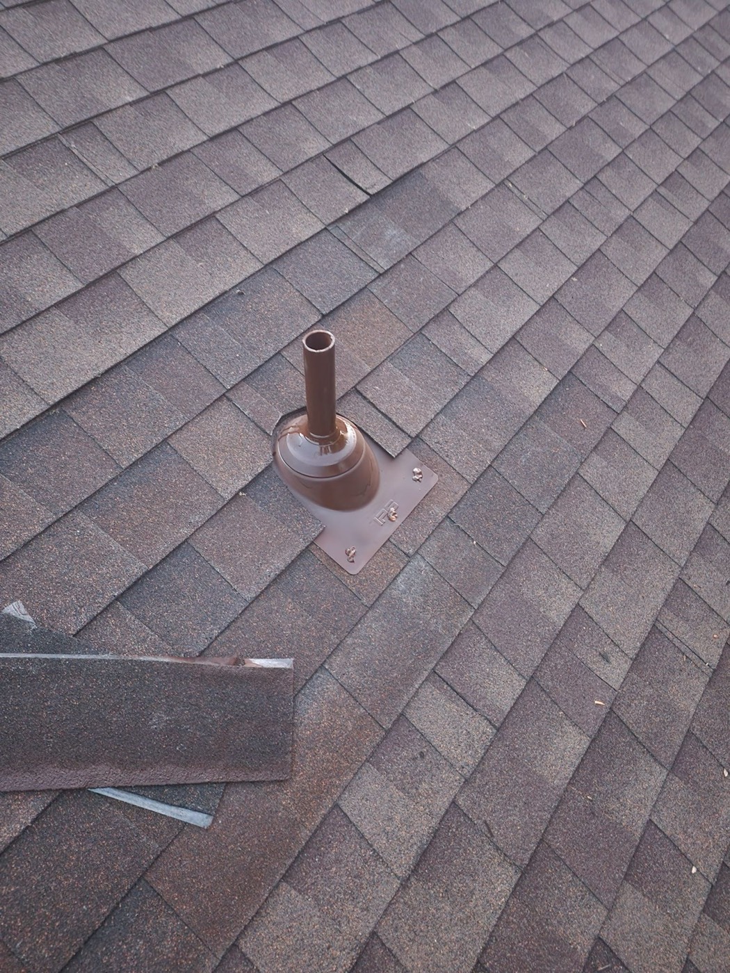 Finished pipe boot installation on the same Lock Lynnhe roof with a new lead-base flashing plate set under the shingle weave and a two-part urethane bead at the collar.