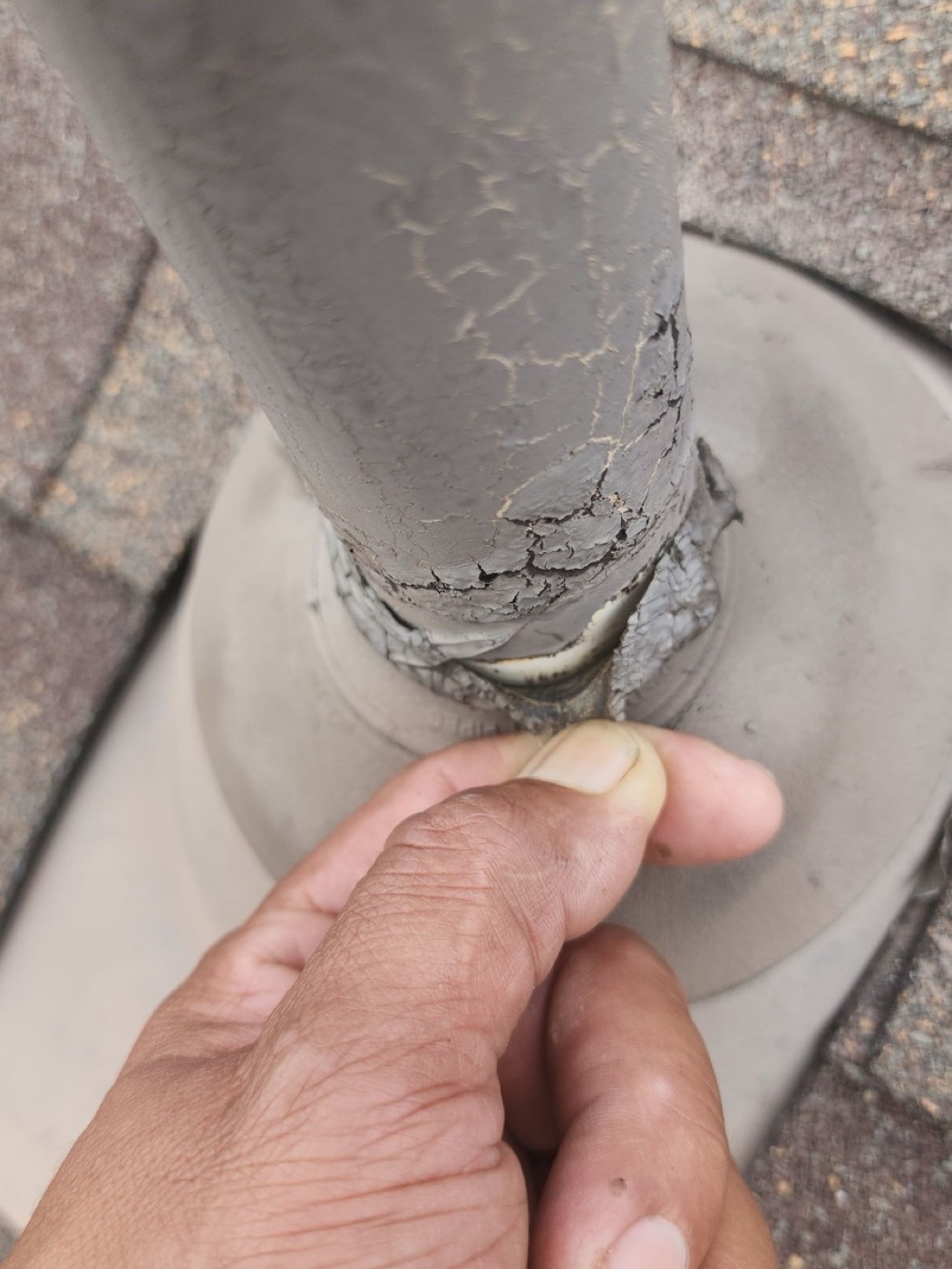 Close-up of a cracked Oatey neoprene pipe boot in Pflugerville on Lock Lynnhe with UV failure and split rubber collar, the most common single cause of ceiling stains around bathroom vents.