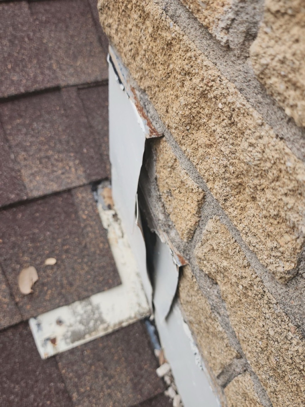 Decayed roof-to-wall step flashing in Pflugerville on Lock Lynnhe with rust perforation and failed sealant, the failure mode that creates sidewall leaks behind a finished interior.