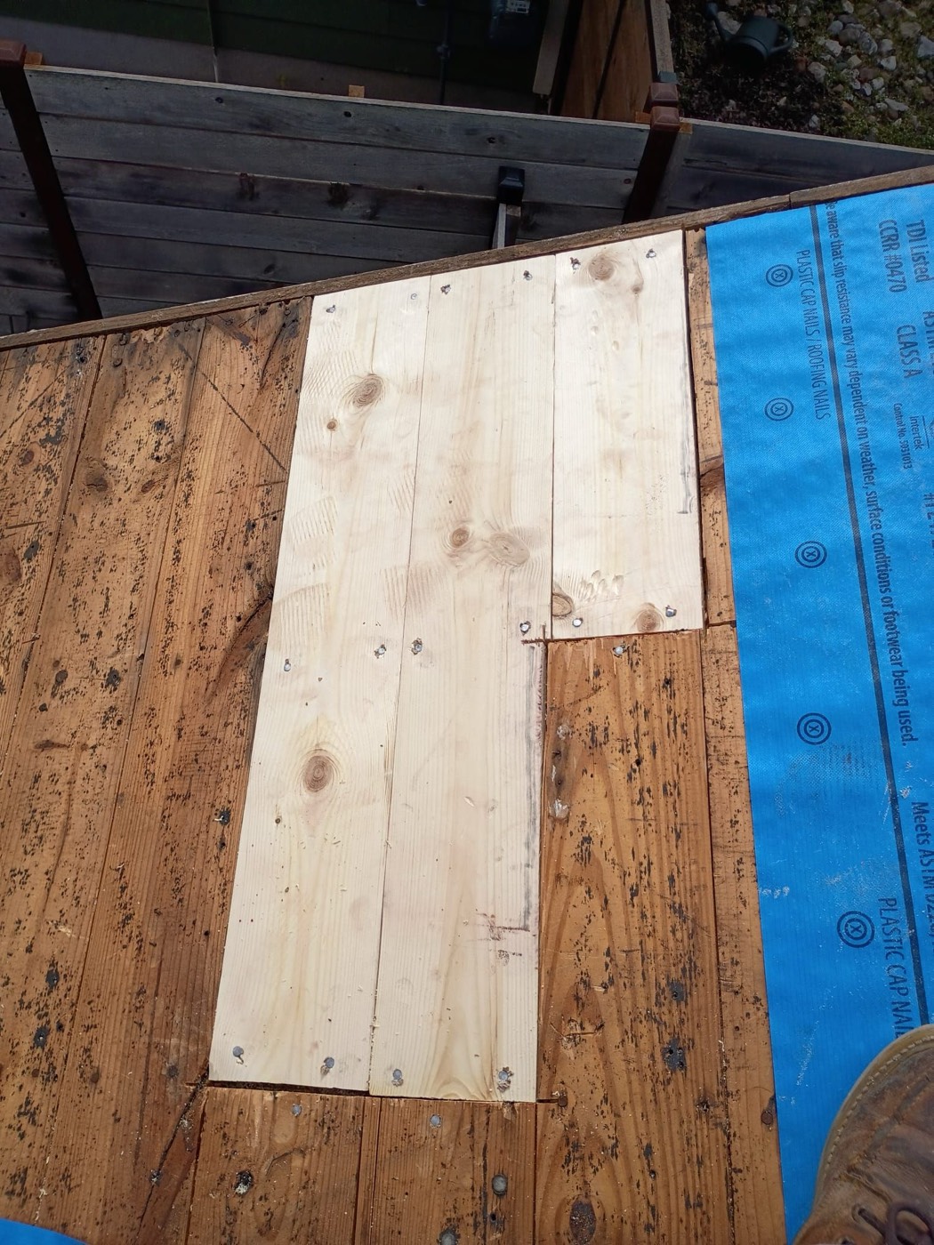 New plywood decking sheet set into the original 1x6 plank decking field on a recent Austin Metro reroof, blue ice and water shield visible at the edge, approved as a supplemental line item.