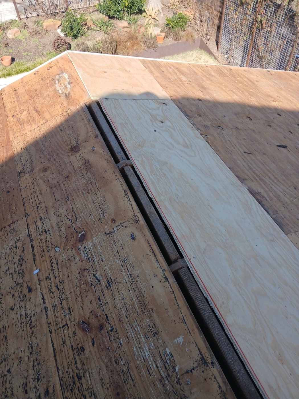 Fresh plywood patch laid over original decking with a red sealant line along the joint, photographed before underlayment goes down. Filed as a code upgrade supplement under Ordinance and Law.